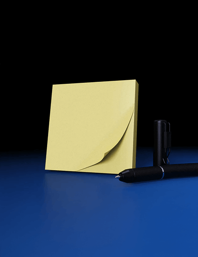 Yellow sticky note and black pen on a blue surface with a black background