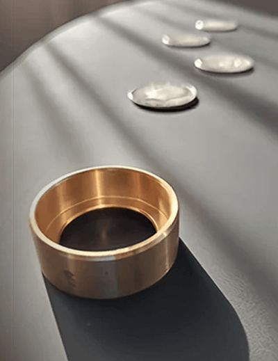 Bronze ring on a reflective surface with coins in the background